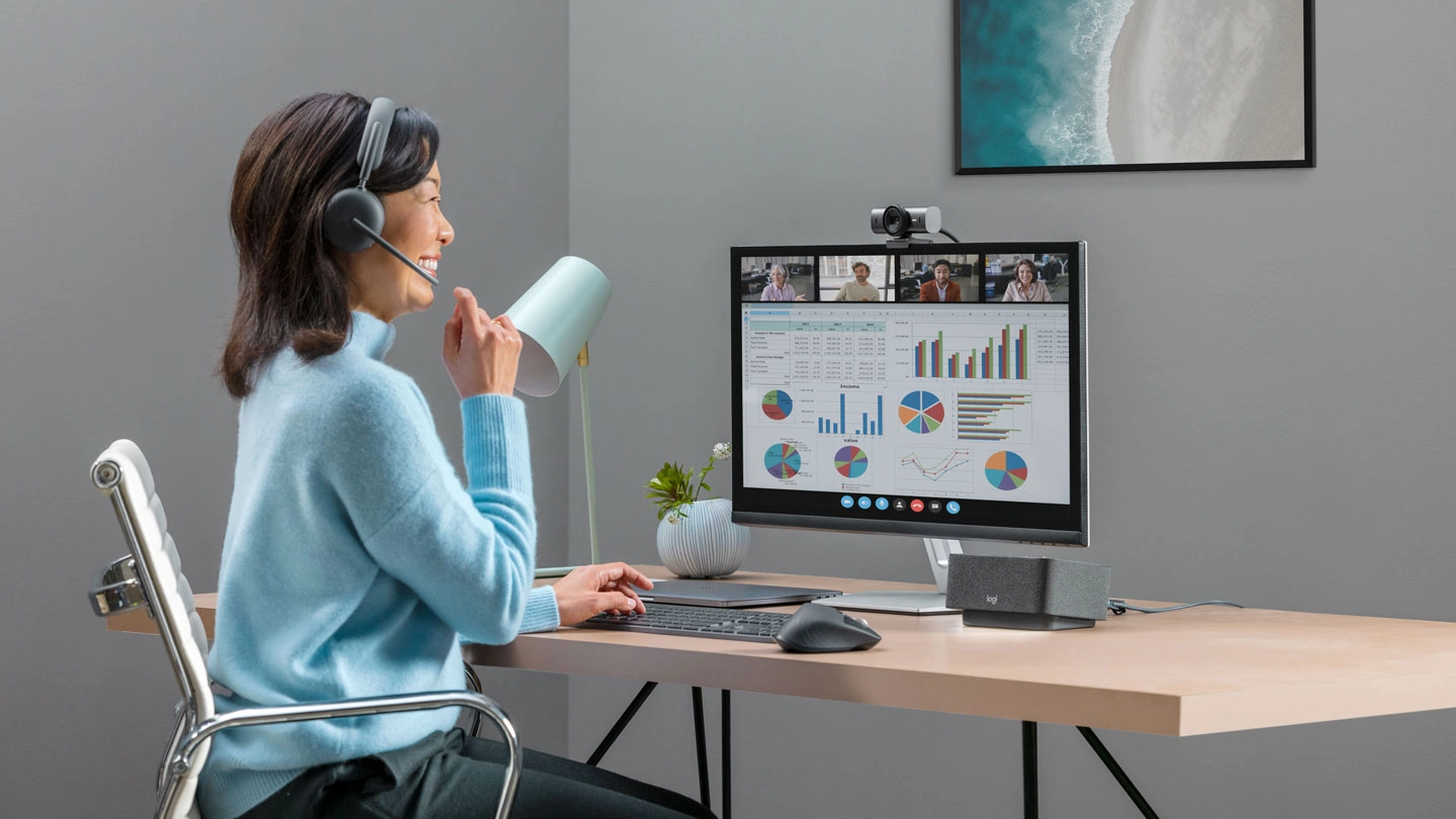 An image of an office working engaged in online meeting with four others, where several bar graphs and pie charts are being presented