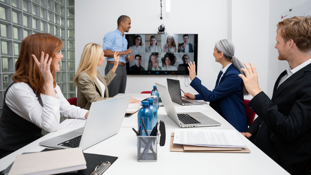 A team of individuals collaborating in a meeting room, focused on their laptops and discussing ideas together